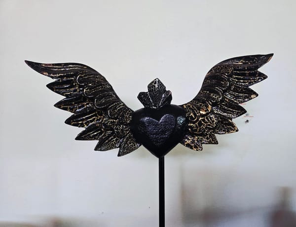 Mexican heart with wings, a folk protective amulet. The gold lines throughout the black reminds me of kintsugi, the Japanese art of pottery repair. There are holes in the wall behind it.